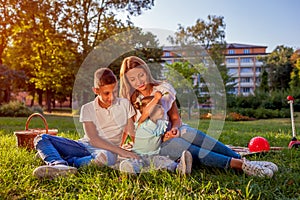 Happy family spending time outdoors sittting on grass in park. Mom with two children smiling. Mother`s day