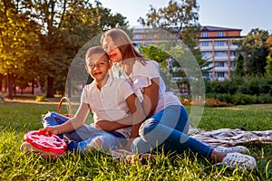 Happy family spending time outdoors sittting on grass in park. Mother with her son hugging and smiling. Family values