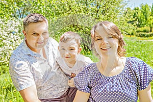 Happy family spending time outdoors on a Sunny summer day. happy mom and dad embrace son in Park on summer Sunny day.