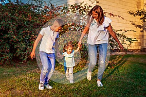 Happy family spending time outdoors walking in park. Mother and her son holding little toddler girl. Mother`s day