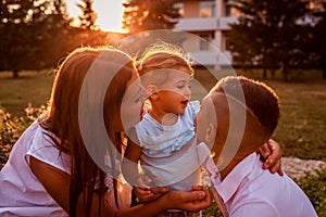 Happy family spending time outdoors walking in park. Mother and her son hugging little toddler girl. Mother`s day