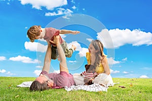 happy family spending time on summer day. Father lifted son into the air while picnicking in the park on a summer day