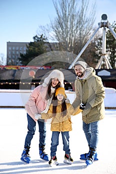Happy family spending time together at ice skating rink