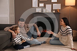 Happy family spending time together near fireplace at home