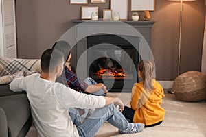 Happy family spending time together near fireplace at home, back view