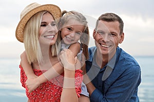 Happy family spending time together near sea on sunny summer day