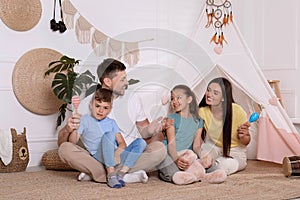 Happy family spending time together near toy wigwam