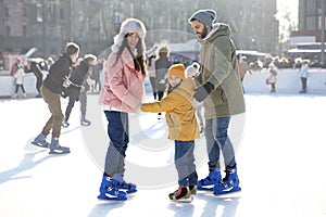 Happy family spending time together at outdoor ice skating rink