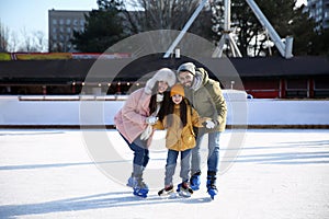 Happy family spending time together at outdoor ice skating rink