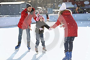 Happy family spending time together at outdoor ice skating rink