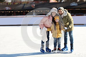 Happy family spending time together at outdoor ice skating rink, space for text