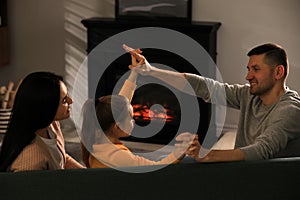 Happy family spending time together on sofa near fireplace at home