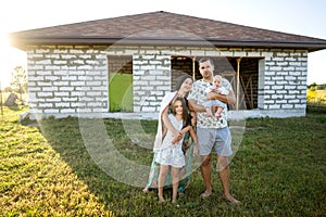 Happy family stand near their new home, construction, dream project, joint construction of a house