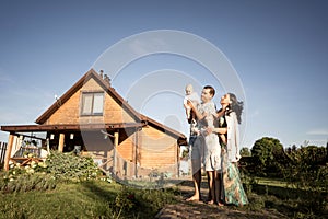 Happy family stand near their new home, joint construction of a house