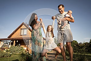 Happy family stand near their new home, joint construction of a house