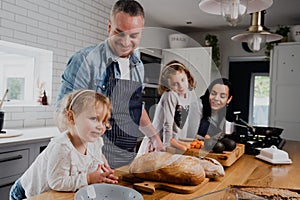 Happy family standing around table kitchen smiling while preparing breakfast.