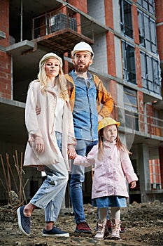 Happy family standing at construction site.