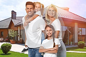 Happy family standing in front of house on sunny day