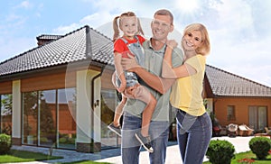 Happy family standing in front of house on sunny day