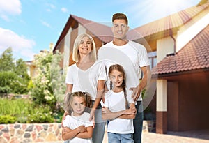 Happy family standing in front of their house