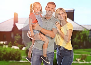 Happy family standing in front of their house