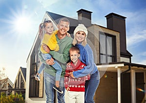 Happy family standing in front of their house on sunny day