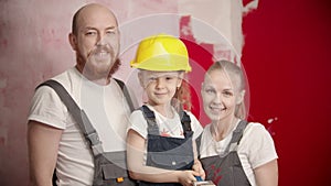 Happy family is standing and looking at the camera daughter is holding a brush