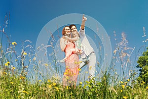 Happy family standing on meadow in summer