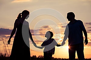 Happy family standing in the park at the sunset time