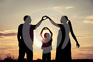 Happy family standing in the park at the sunset time