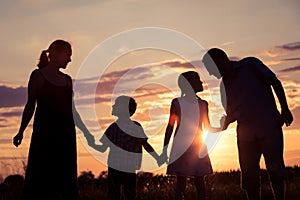 Happy family standing in the park at the sunset time