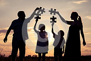 Happy family standing in the park at the sunset time