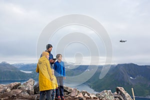 Happy family, standing on a rock and looking over Segla mountain on Senja island, North Norway, taking pics with drone. Amazing