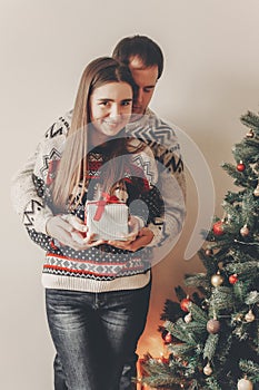 happy family in stylish sweaters exchanging gifts in festive room with christmas tree and lights. emotional moments. merry christ