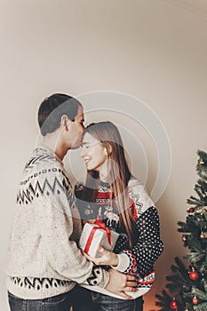 happy family in stylish sweaters exchanging gifts in festive room with christmas tree and lights. emotional moments. merry christ