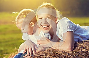Happy family in summer nature. Mother and baby daughter in the hay, straw