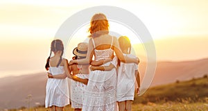 Happy family in summer outdoors. Mother  hug children daughters on sunset