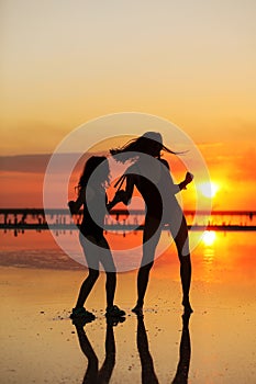 Happy family summer travel holiday. Silhouette of active mom with teen child daughter having fun dancing together on