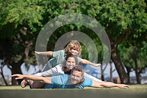 Happy family on summer walk. Father mother and child walking in the park. Parents giving child piggybacks in countryside