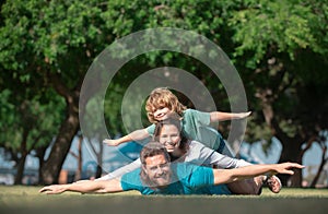 Happy family on summer walk. Father mother and child walking in the park. Parents giving child piggybacks in countryside