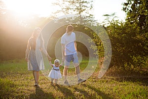 Happy family at sunset. Father, mother and child daughter having fun and playing.