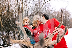 Happy family at sunset. Father, mother and child daughters are having fun and playing on snowy winter walk in nature, kiss. Frost