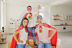 Happy family of superheroes laughing in a room indoors.
