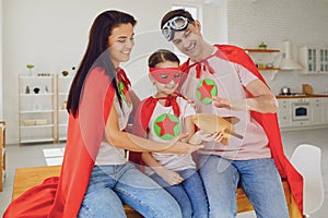 Happy family of superheroes in a room indoors.