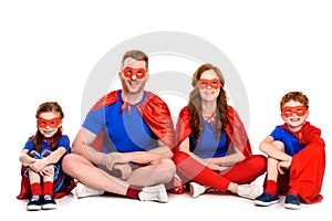 happy family of superheroes sitting together and smiling at camera