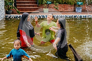 Happy Family swimming in the pool. Mother wearing hijab with children