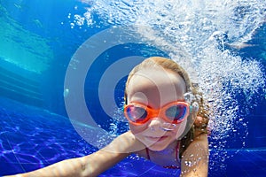 Funny child in goggles dive in swimming pool photo