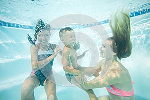 Happy family swimming underwater. Mother, son and daughter having having fun in pool.