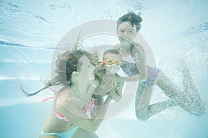 Happy family swimming underwater. Mother, son and daughter having having fun in pool.