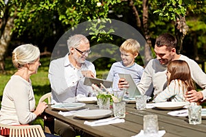 Happy family with tablet pc at table in garden